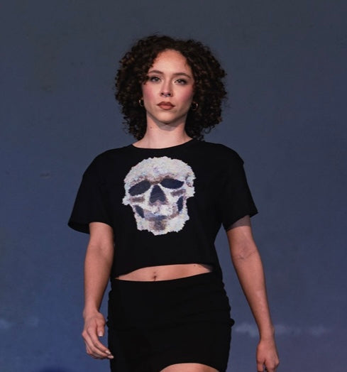 Model wearing a black t-shirt with a skull design on a dark background