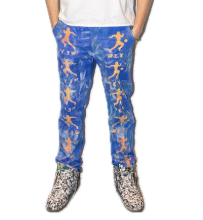 Person wearing a white t-shirt with colorful graphics and blue pants with orange patterns on a white background