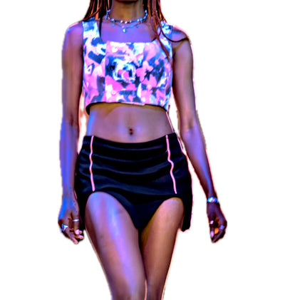 Woman wearing a colorful floral top and black shorts on a white background