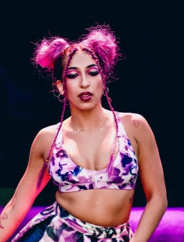Woman in a colorful outfit with pink hair on a stage