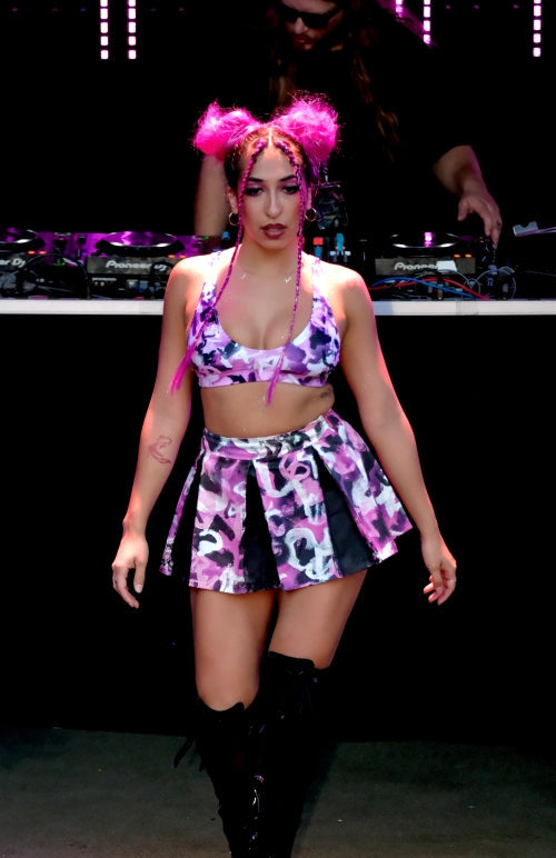 Person in a colorful outfit with pink hair on a stage